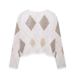 Détail du cardigan blanc à paillettes montrant des motifs de losanges marron