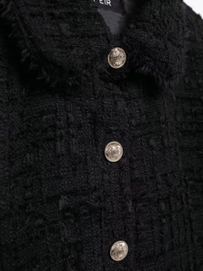 Macro shot of black tweed fabric texture and detailed gold embossed metal buttons