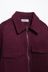 Dettaglio della giacca in lana bordeaux con tasche a patta e cerniera in metallo