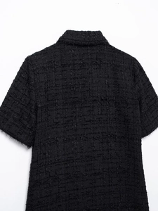 Macro detail of black tweed short-sleeve top showing rich woven texture and frayed edges