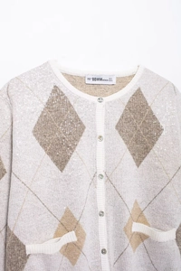 Gros plan du cardigan en maille à losanges avec paillettes et encolure ronde élégante