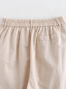Detail view of beige linen pants featuring an elastic waistband and back slit pocket