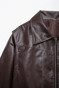 Détails d'une veste en cuir marron foncé avec coutures blanches et fermeture éclair argentée