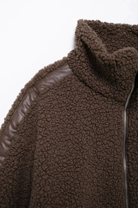Close-up of brown faux shearling jacket with high collar and leather shoulder piping