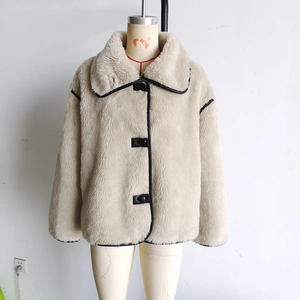 Detail of faux shearling jacket featuring wide collar, black leather trim, and large buttons