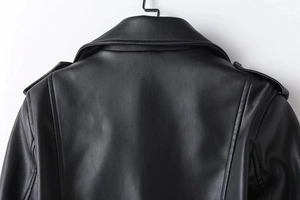 Detail view of black faux leather jacket showing premium texture and shoulder stitching