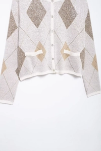 Détail du cardigan en tricot avec motif losanges à paillettes et boutons argentés