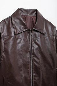 Détail d'une veste en similicuir marron chocolat avec surpiqûres blanches contrastées
