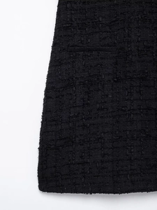 Detailed macro view of black tweed fabric texture with fringe edges and woven patterns