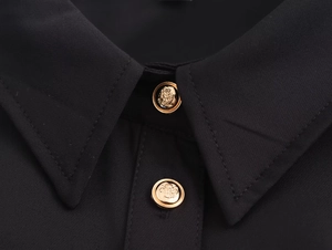 Dettaglio dell'elegante colletto nero con bottoni dorati a rilievo e cuciture rifinite