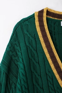 Detail of dark green cable knit cardigan featuring striped V-neck and rich texture
