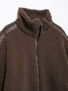 Close-up of brown teddy fleece jacket featuring leather piping and silver zipper detail