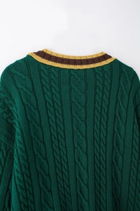 Macro detail of cable-knit texture and striped V-neckline on dark green knit sweater