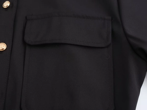Dettaglio dell'abito midi nero in twill con tasca a patta e bottoni dorati