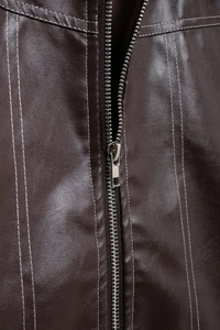 Détail de la veste en similicuir marron avec fermeture éclair argentée et coutures blanches