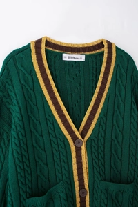 Close-up of cable knit texture and contrasting striped V-neckline on dark green cardigan