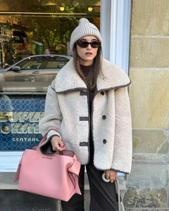 Detail of faux shearling jacket with turn-down collar and contrast piping on the street
