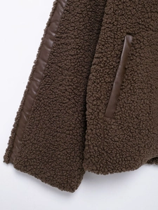 Close-up of brown faux shearling jacket featuring dark leather piping and pocket detail