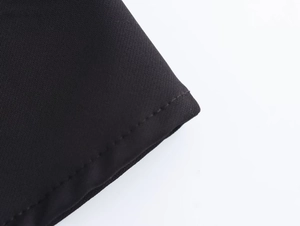 Dettaglio della trama del tessuto nero e cuciture precise sull'abito midi elegante
