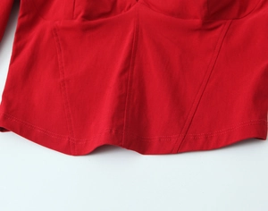 Detail view of red corset top showing structural seam lines and double needle stitching