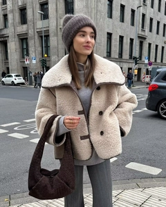 Detail of faux shearling coat featuring contrast brown trim and large dark buttons