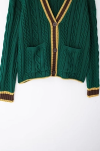 Detail of cable knit pattern and striped cuffs on dark green V-neck cardigan