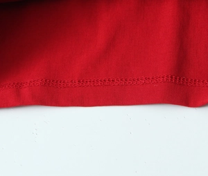 Detailed close-up showing the precise double-needle stitching on red knit cotton fabric