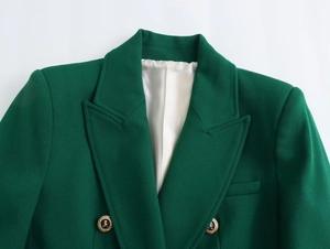 Dettaglio del blazer verde scuro con bottoni dorati a testa di leone e revers a punta