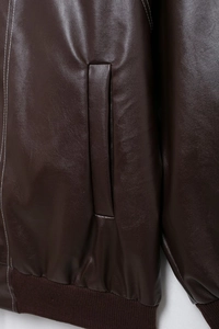Détail de veste en cuir marron foncé avec surpiqûres blanches et ourlet côtelé
