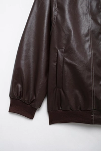 Détail de veste en cuir marron foncé avec surpiqûres blanches et poignets côtelés