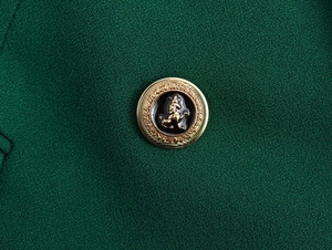 Macro di un bottone con stemma di leone vintage dorato su tessuto blazer verde bosco