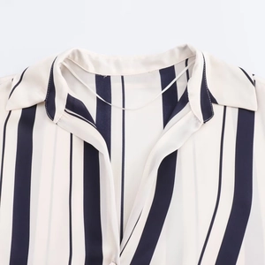Detail of white striped satin shirt featuring a flat lapel collar and V-neckline texture