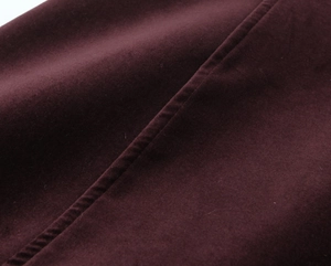 Détail du tissu en velours bordeaux avec des coutures de qualité sur la robe