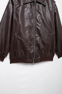 Détails de veste en similicuir marron avec coutures contrastées blanches et bords-côtes