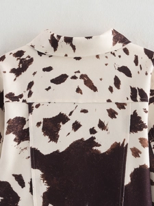 Détail de la veste à imprimé vache avec col et coutures précises sur tissu tissé