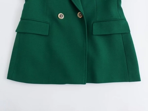 Dettaglio del blazer verde scuro con tessuto strutturato e bottoni dorati a leone