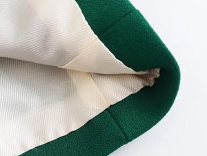 Dettaglio dell'orlo in tweed verde con fodera in seta beige liscia e rifinita
