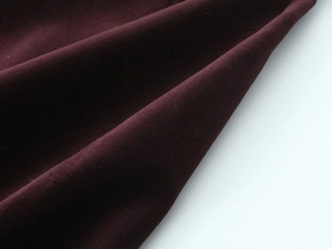 Détail macro du tissu en velours bordeaux profond montrant sa texture douce et soyeuse