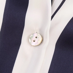 Detail of blue and white striped satin fabric with a shimmering mother-of-pearl button