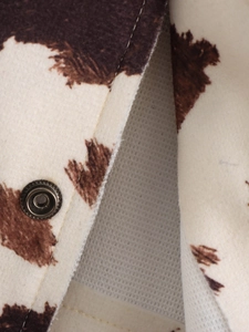 Détail de la veste en laine imprimé vache avec bouton pression et surpiqûres