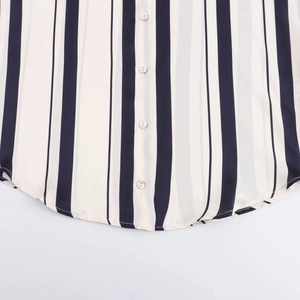 Detail of striped satin shirt featuring a button-down front and curved hemline