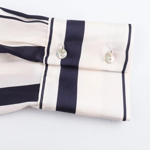 Detail of silk-satin shirt cuff with black and white vertical stripes and pearl buttons