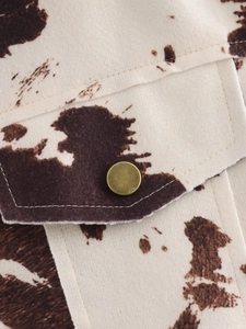 Détail du tissu en laine à motif vache avec une poche et un bouton en métal vintage