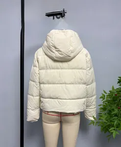 Detail of beige quilted hooded puffer jacket showing the back view and soft material texture