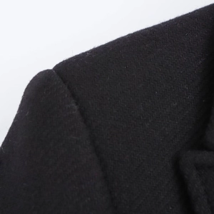 Close-up of the professional shoulder stitching and black wool blend fabric on a long coat