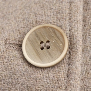 Détail d'un bouton imitation bois sur un manteau en laine de couleur camel clair