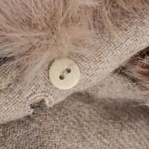 Détail du manteau en laine avec col en fausse fourrure et bouton en résine poli