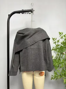 Detailed close-up of dark grey knitted wrap jacket featuring an asymmetric scarf collar
