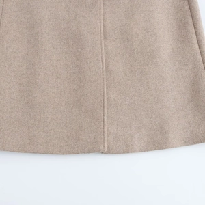 Vue détaillée des coutures fines et de la texture en laine sur l'ourlet d'un manteau beige