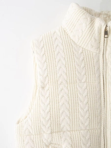 Detaillierte Nahaufnahme der cremeweißen Strickweste mit Zopfmuster und Goldzipper